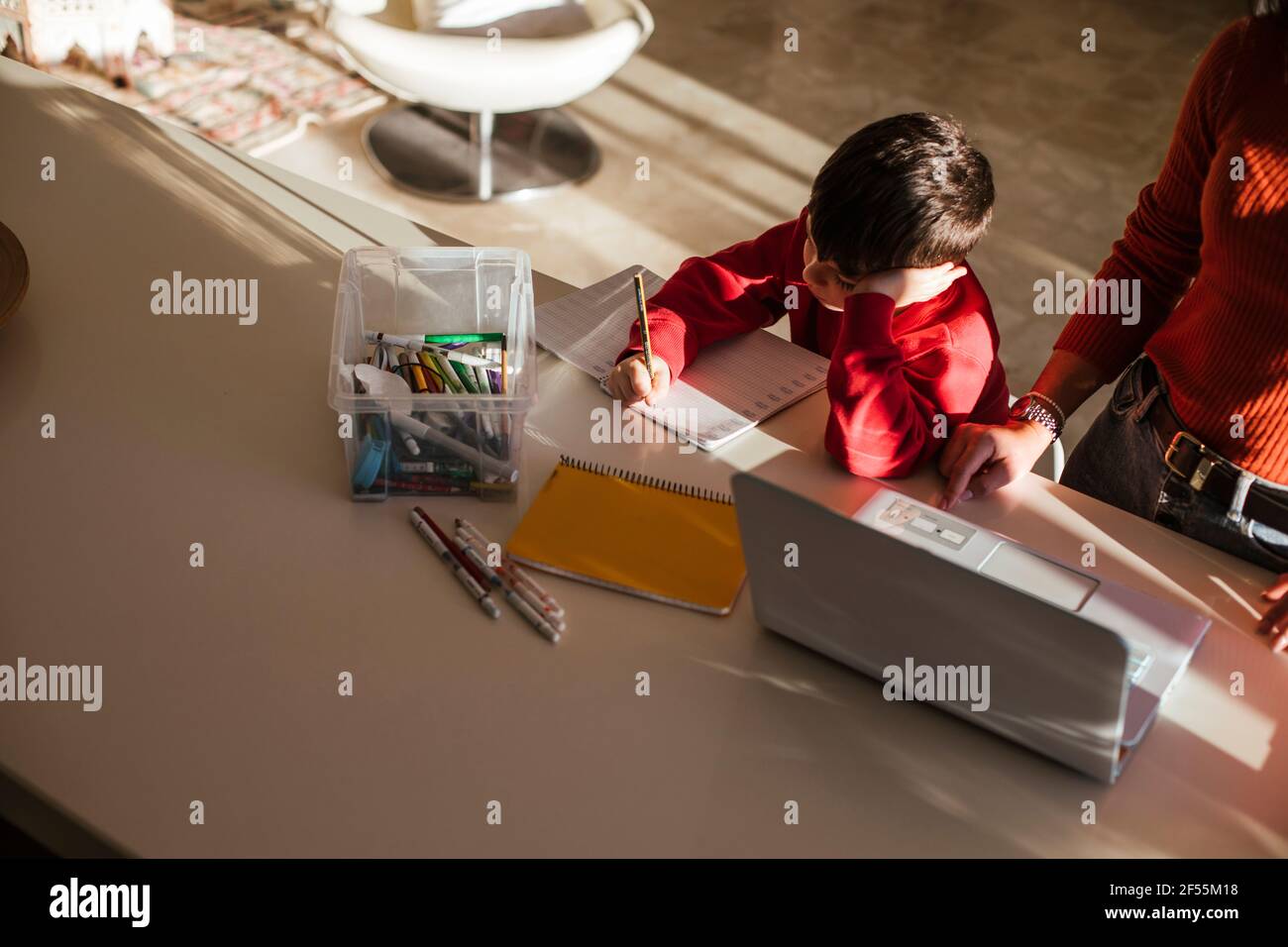Mother assisting son while studying at dining table at home Stock Photo