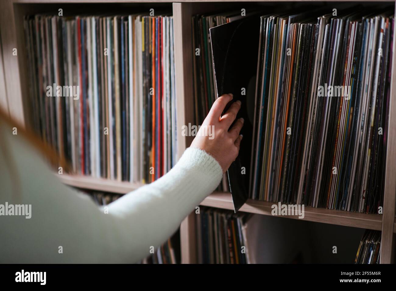 Woman collecting record from shelf at music store Stock Photo