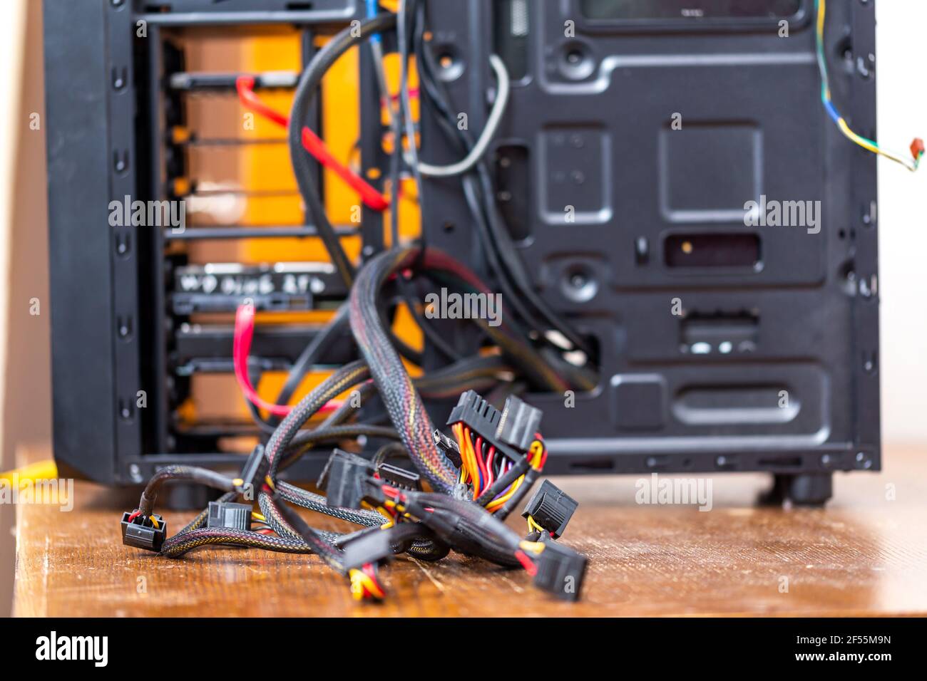 bunch of computer power supply wires sticking out from opened black pc case - close-up with selective focus. Stock Photo