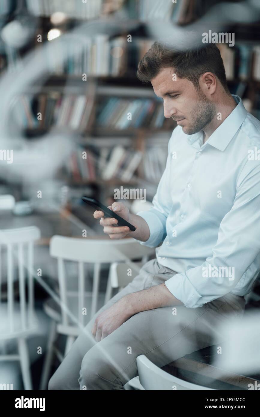Businessman using mobile phone while sitting at cafe Stock Photo