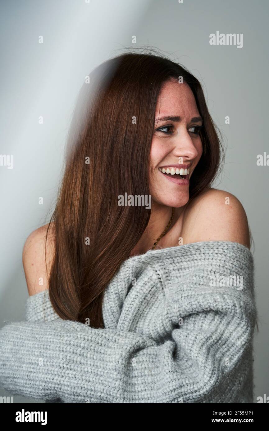 Smiling brown haired woman in sweater looking away Stock Photo