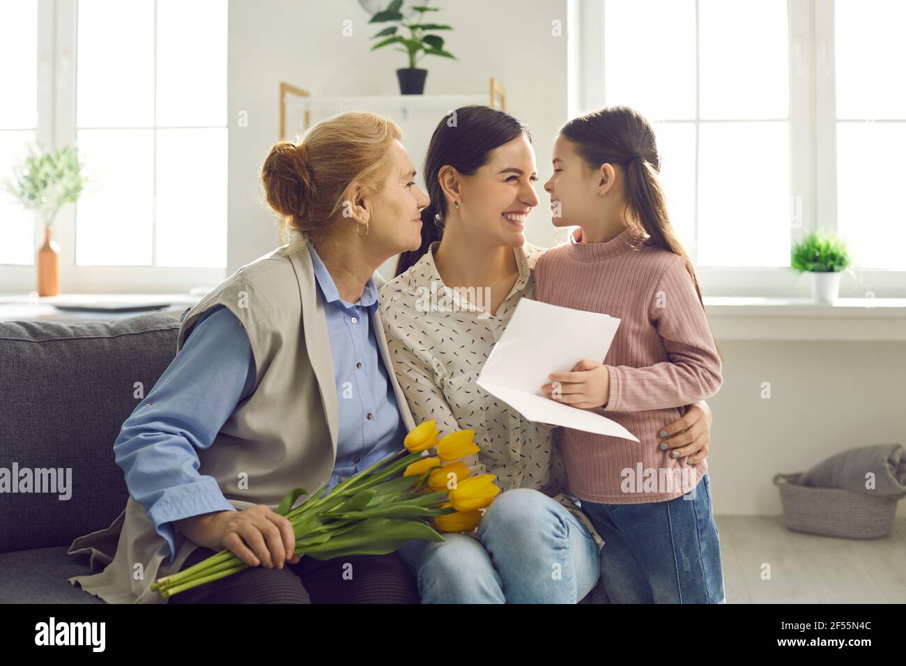 Little girl congratulates her mother and grandmother on the holiday by giving them gifts. Stock Photo