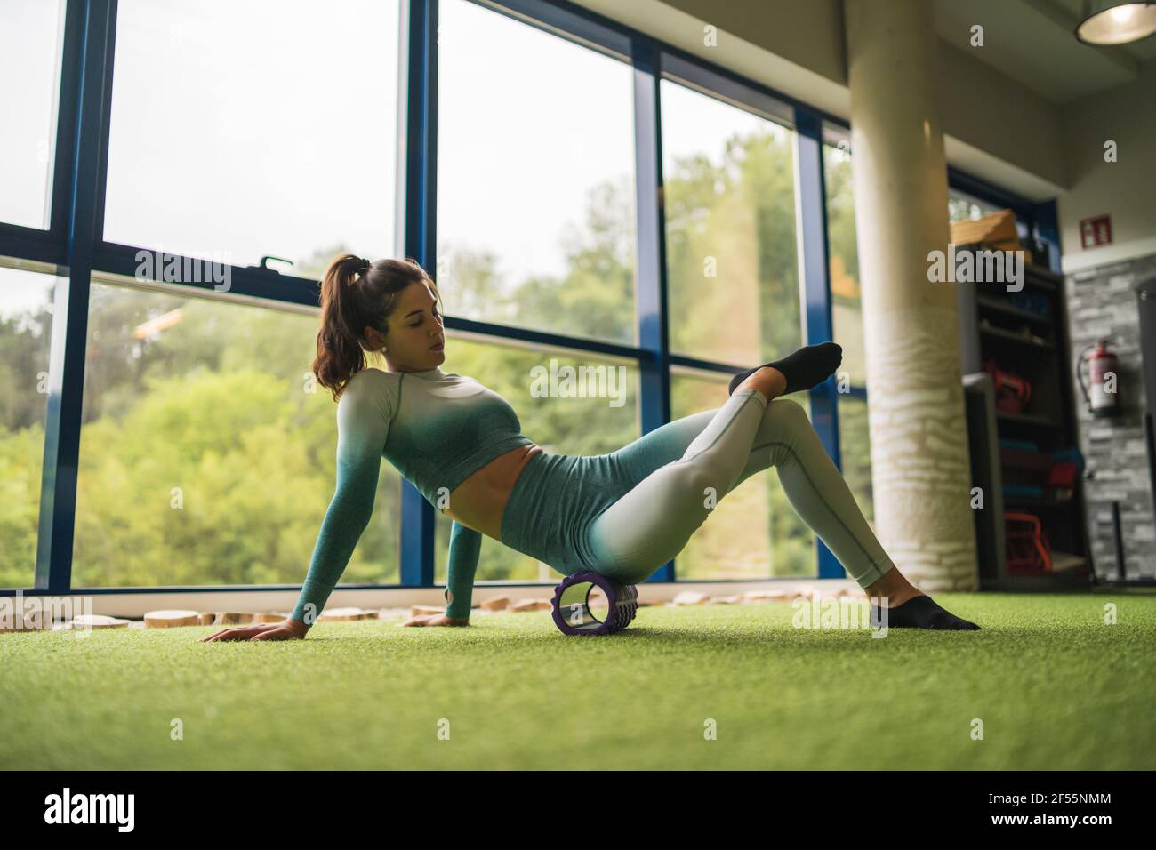 Female athlete exercising with foam roller at health club Stock Photo