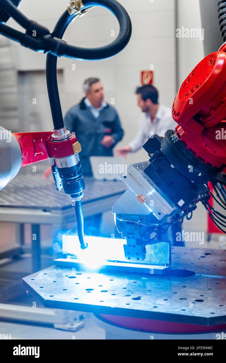 Robotic welding torch welding while male entrepreneurs working in factory Stock Photo Alamy
