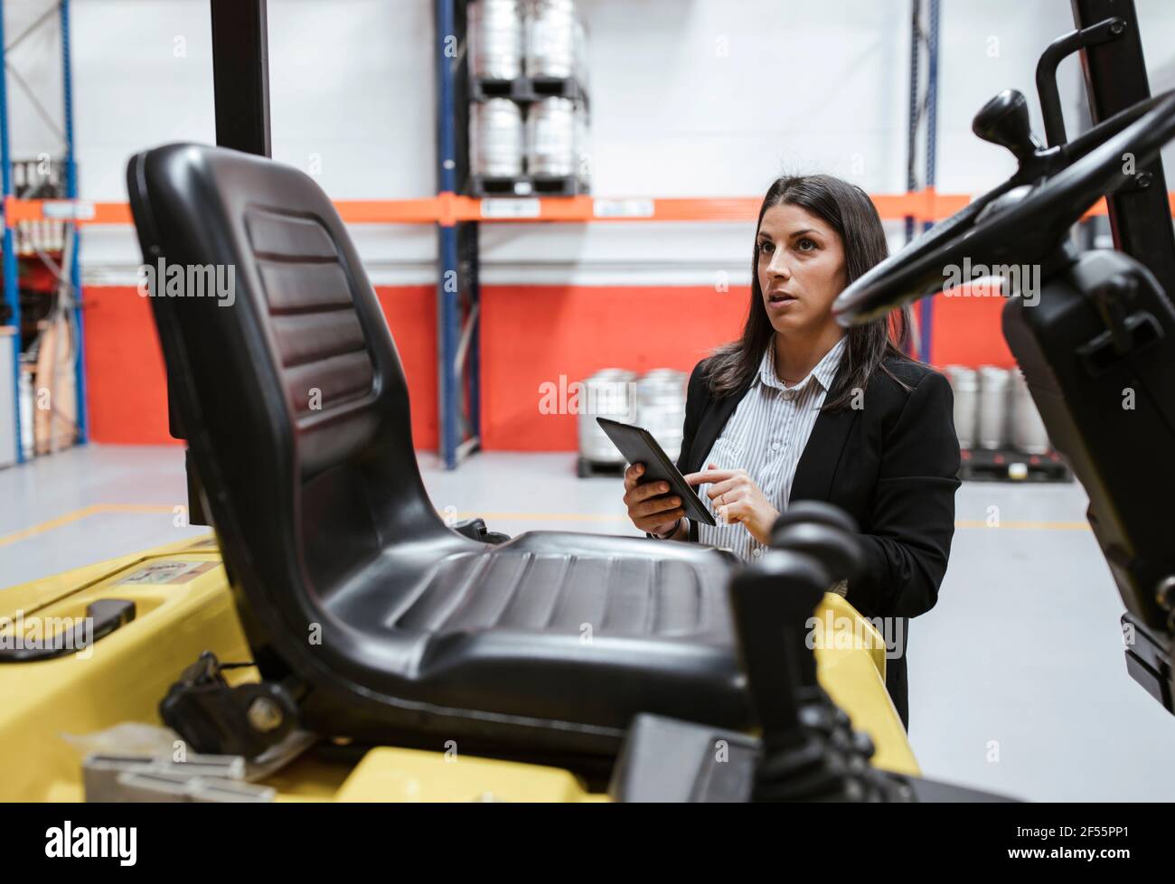 Confident female manager using digital tablet at illuminated warehouse Stock Photo