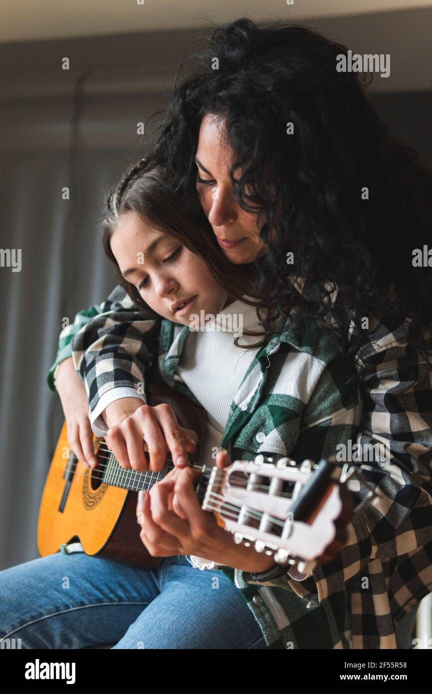 Mother teaching little daughter how to play acoustic guitar Stock Photo
