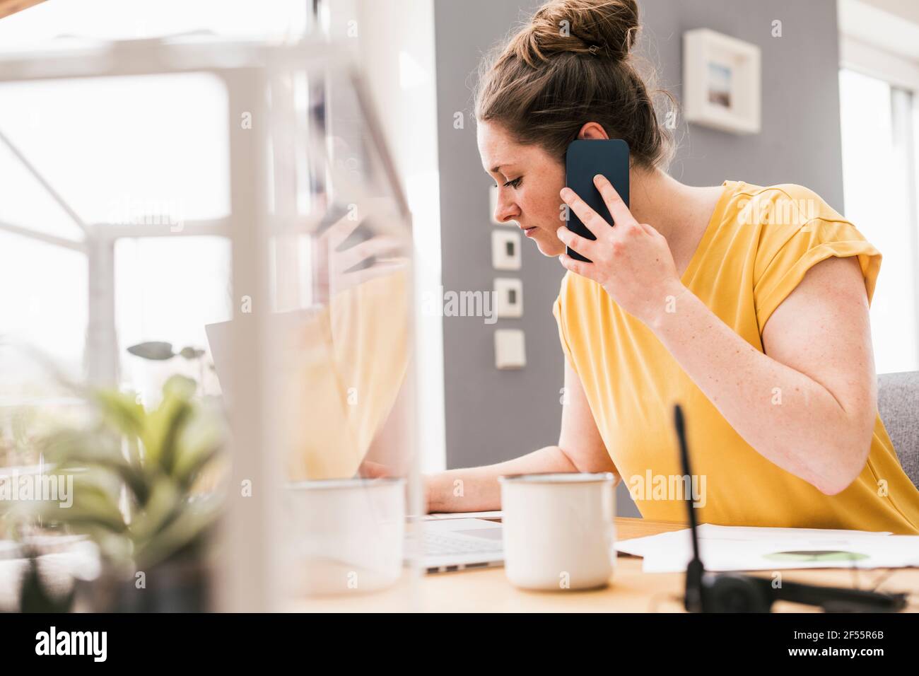 Female entrepreneur working while talking on smart phone Stock Photo
