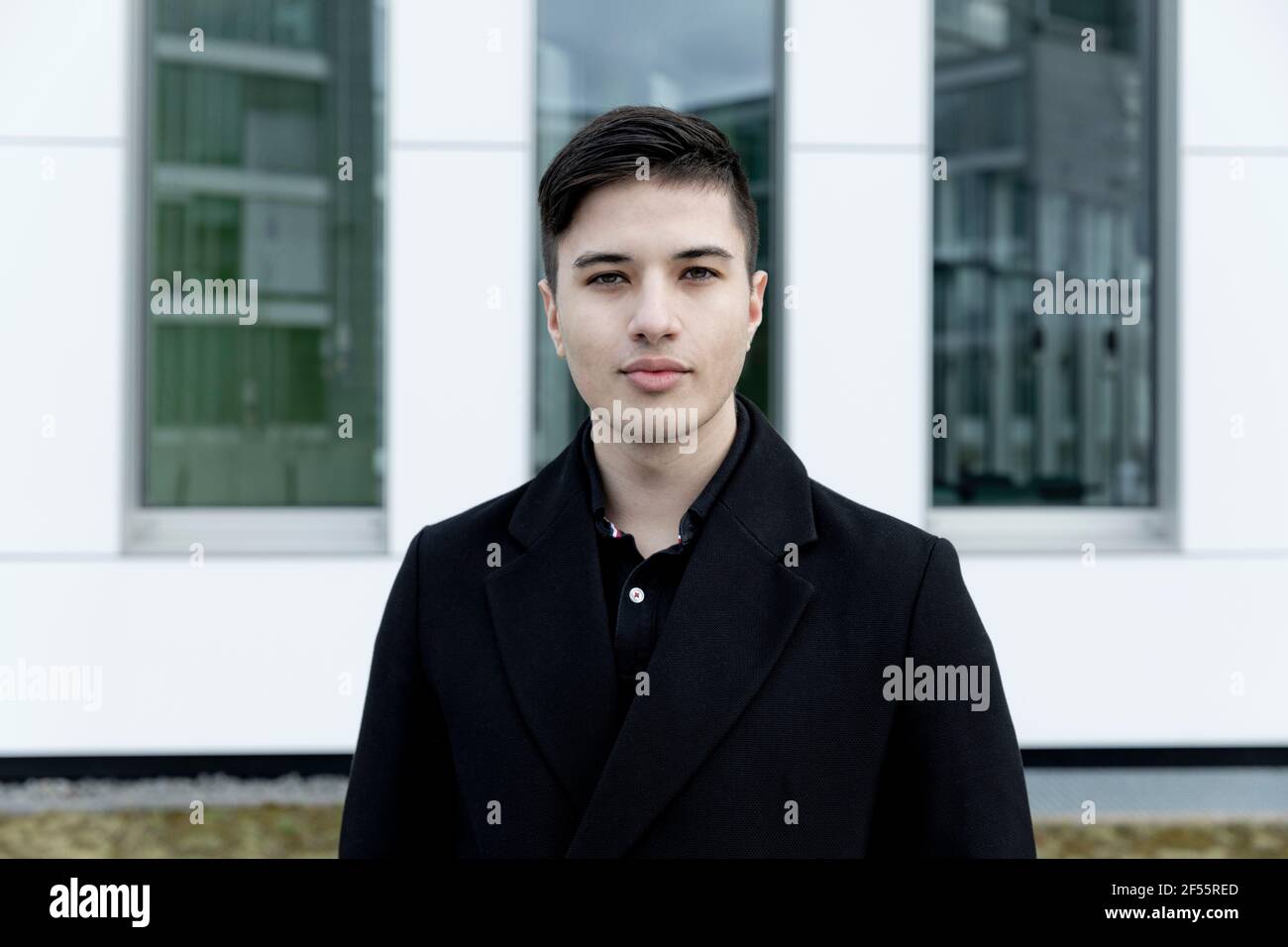 Young businessman standing against office building Stock Photo