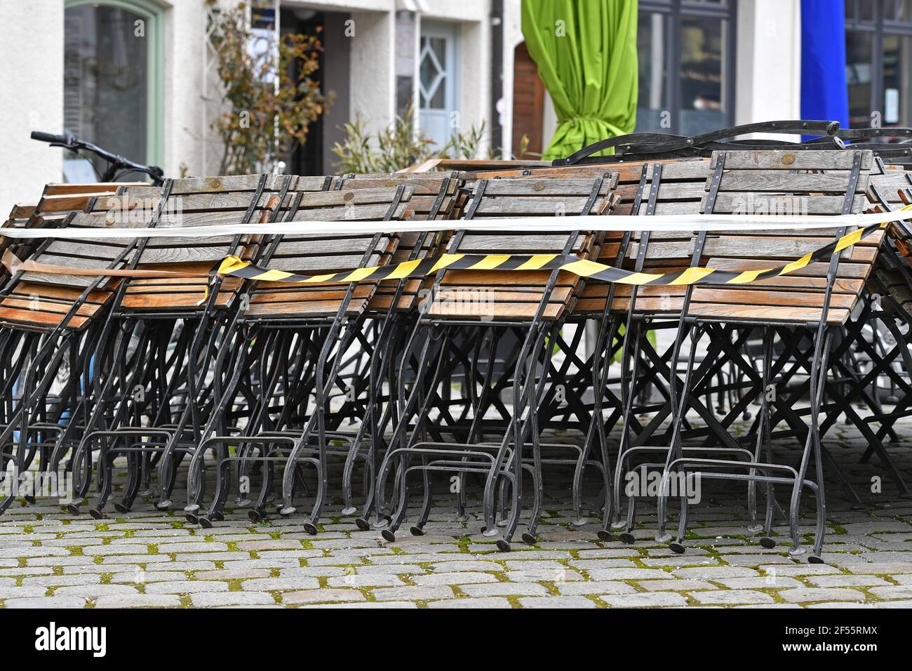 Munich, Deutschland. 23rd Mar, 2021. Topic picture: Coronavirus pandemic/consequences for gastronomy: stacked and folded chairs in front of a restaurant, outdoor gastronomy on March 23, 2021. | usage worldwide Credit: dpa/Alamy Live News Stock Photo