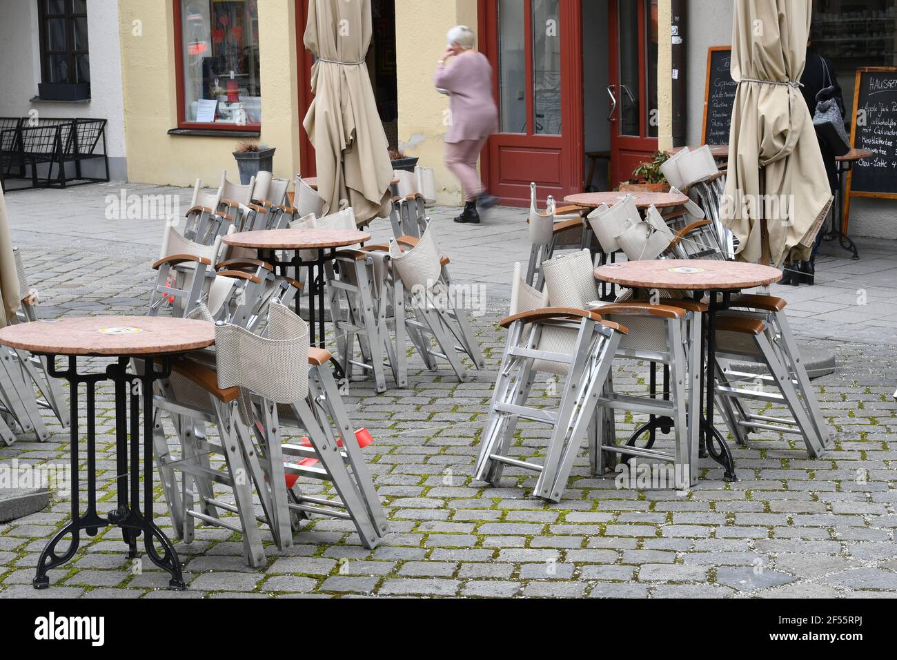 Munich, Deutschland. 23rd Mar, 2021. Topic picture: Coronavirus pandemic/consequences for gastronomy: stacked and folded chairs and tables in front of a restaurant, outdoor catering on 23.03.2021. | usage worldwide Credit: dpa/Alamy Live News Stock Photo