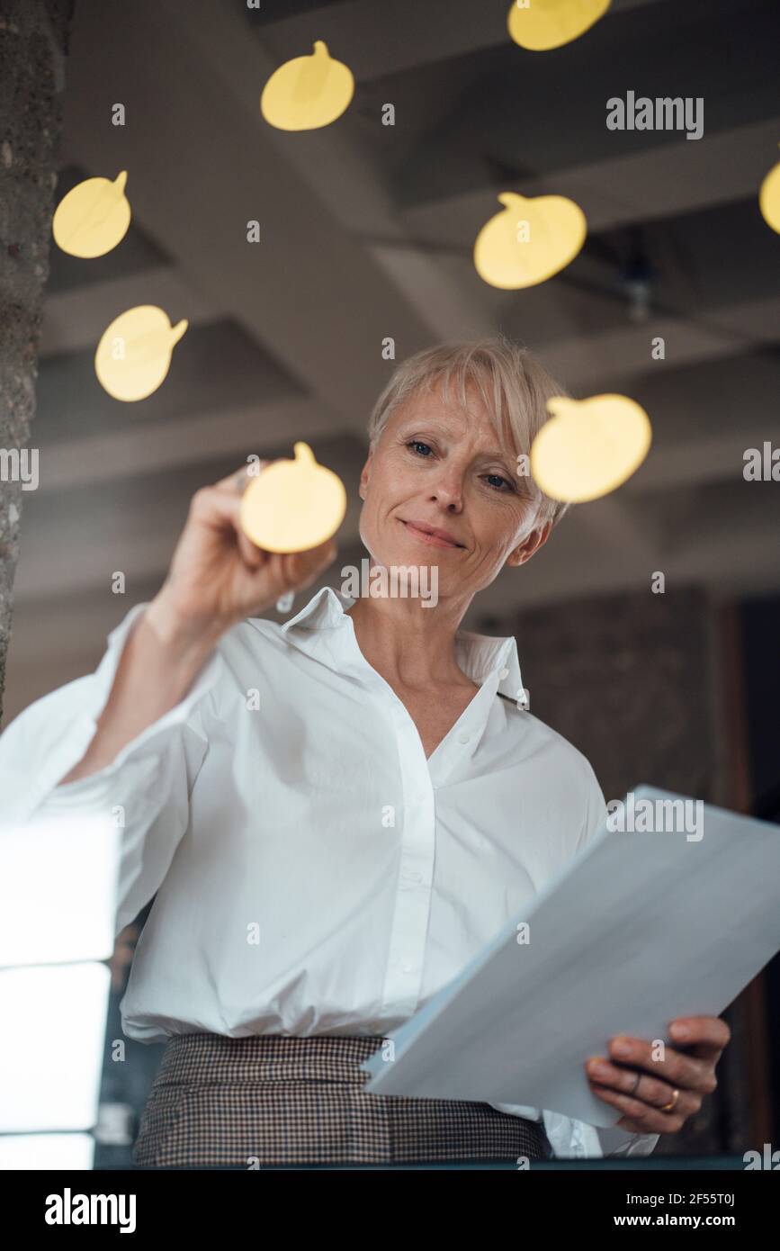 smart businesswoman standing near white flipchart, attaching sticky notes  with copy space Stock Photo by LightFieldStudios