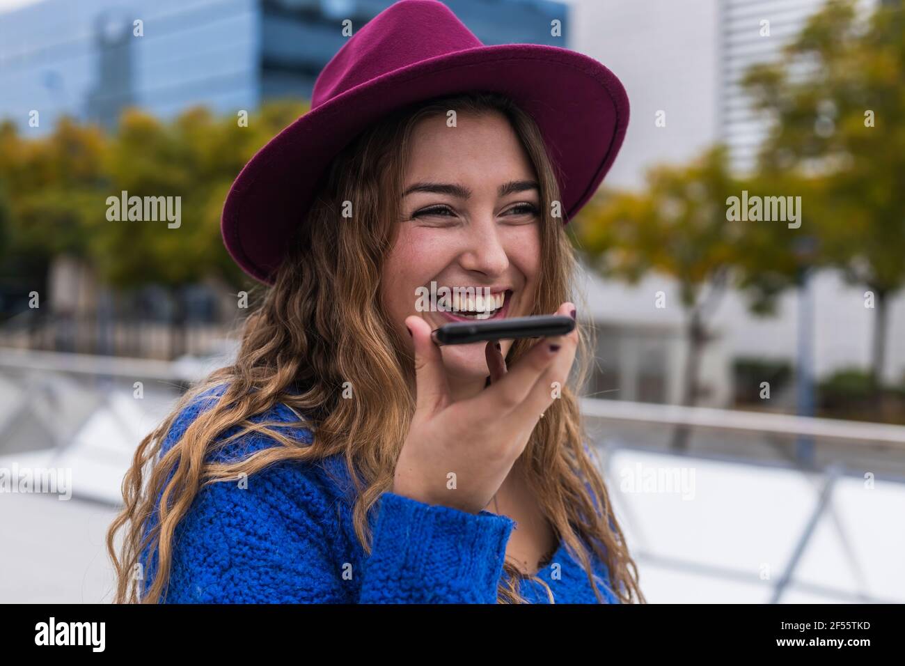 Happy woman laughing while sending voicemail through mobile phone Stock Photo