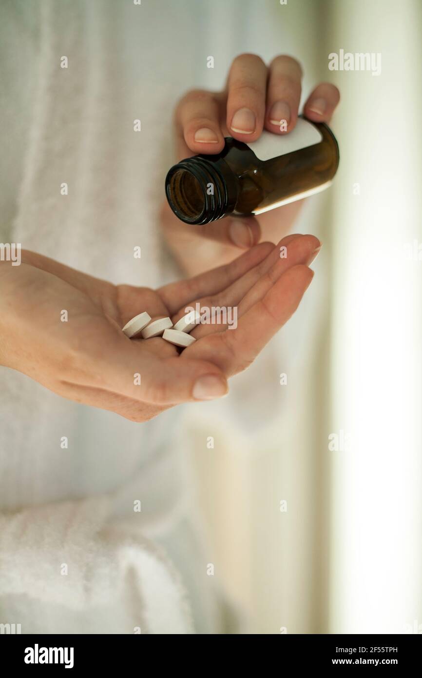 Young woman's hands taking medicine at home Stock Photo