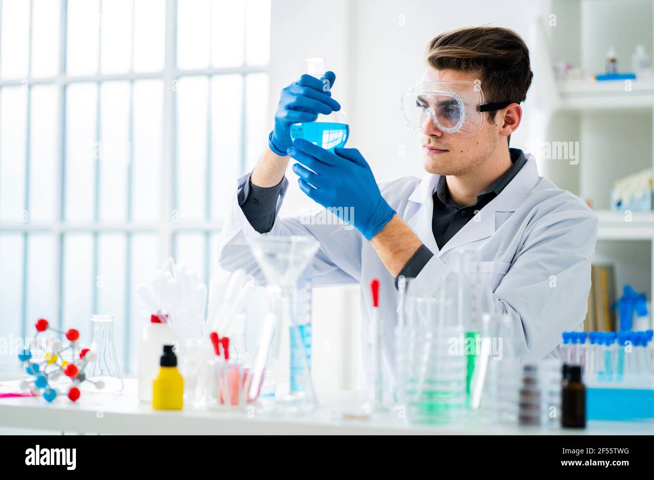 Young scientist measuring chemical in flask at laboratory Stock Photo