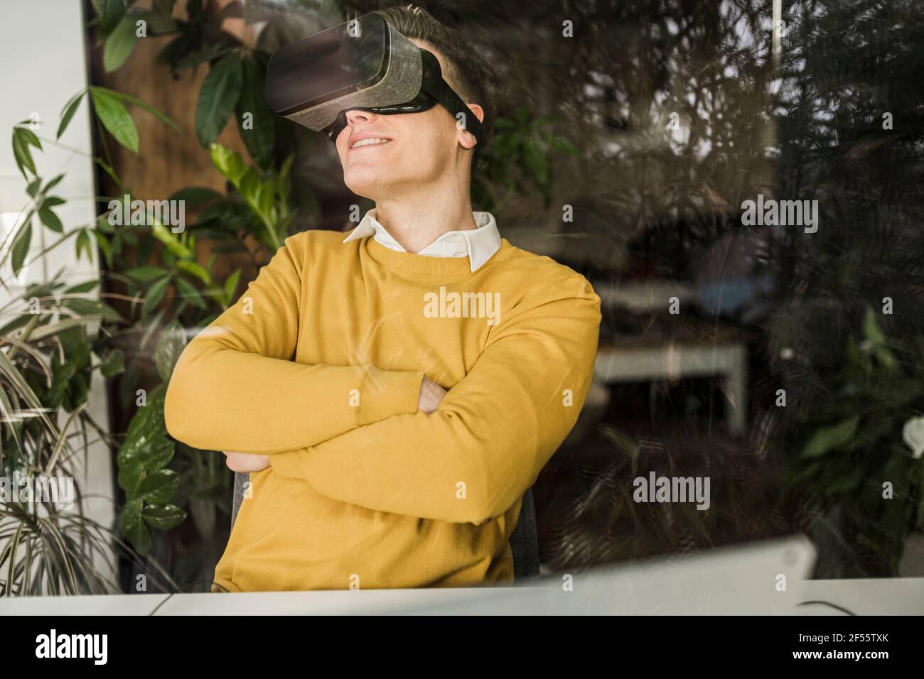 Smiling male entrepreneur wearing virtual reality simulator seen through window in home office Stock Photo