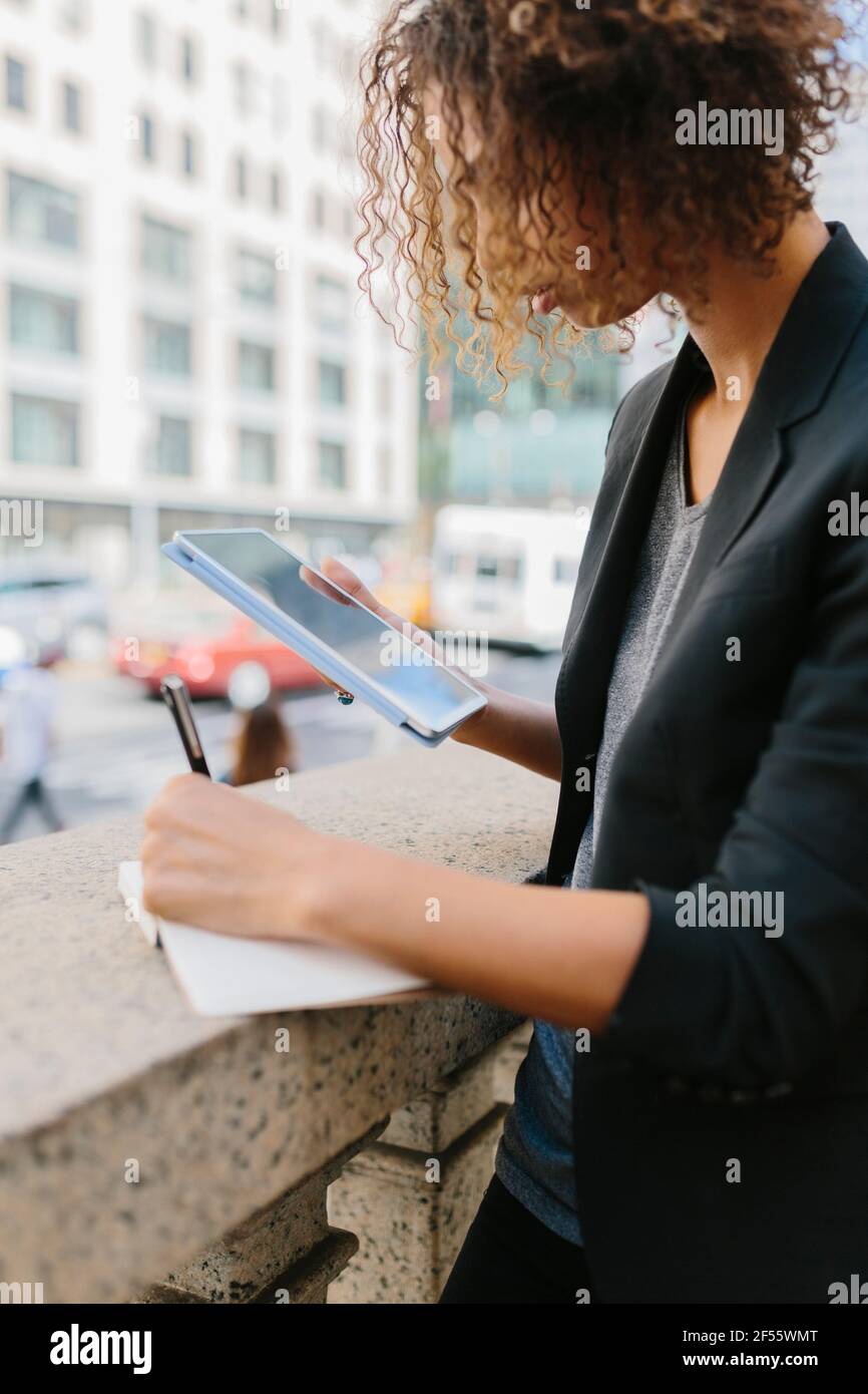Young businesswoman writing in diary using digital tablet Stock Photo