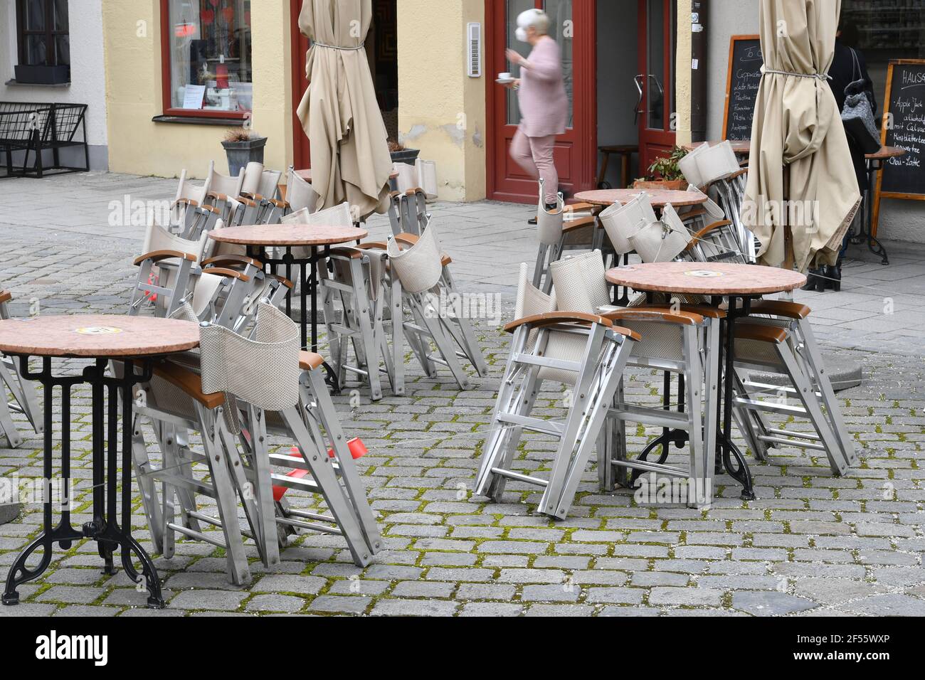 Munich, Deutschland. 23rd Mar, 2021. Topic picture: Coronavirus pandemic/consequences for gastronomy: stacked and folded chairs and tables in front of a restaurant, outdoor catering on 23.03.2021. | usage worldwide Credit: dpa/Alamy Live News Stock Photo