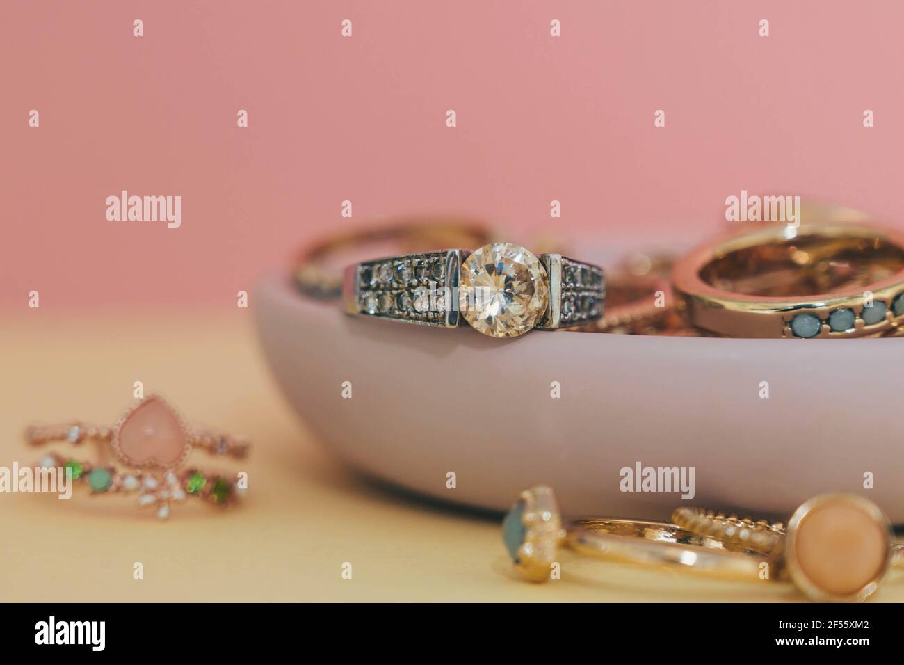Shiny gold and silver jewellery on pastel pink and yellow background