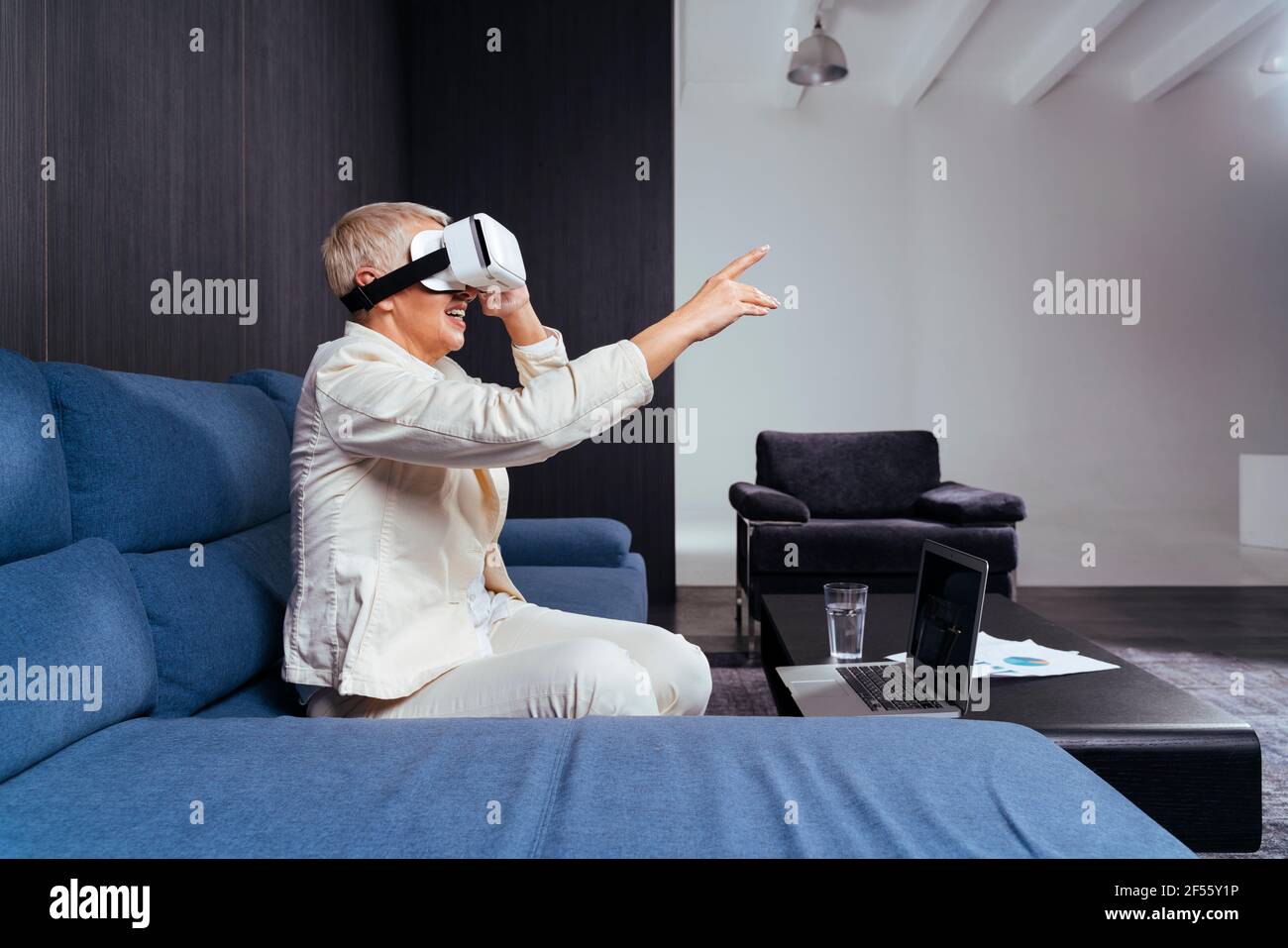 Senior businesswoman gesturing while using virtual reality headset on sofa Stock Photo