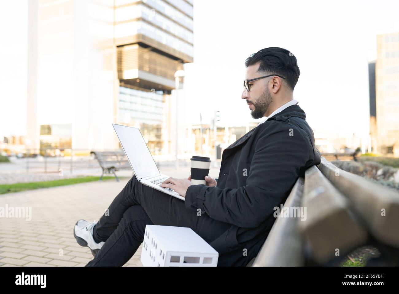 Male architect using laptop while sitting on bench in city Stock Photo