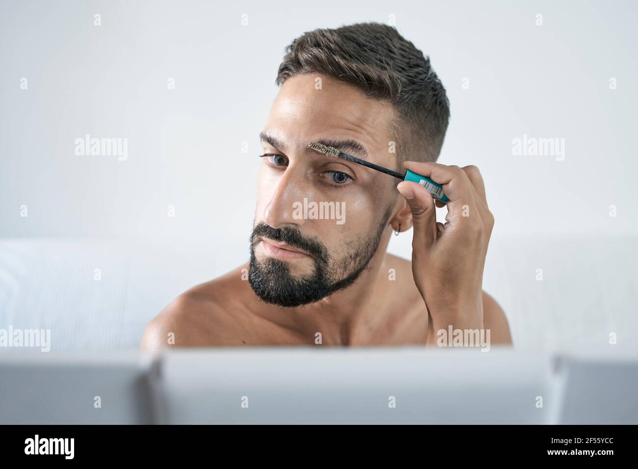 Man brushing eyebrow in front of mirror at home Stock Photo