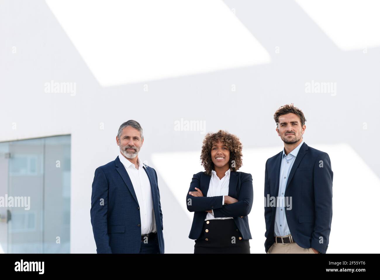 Confident business people standing against white wall Stock Photo - Alamy