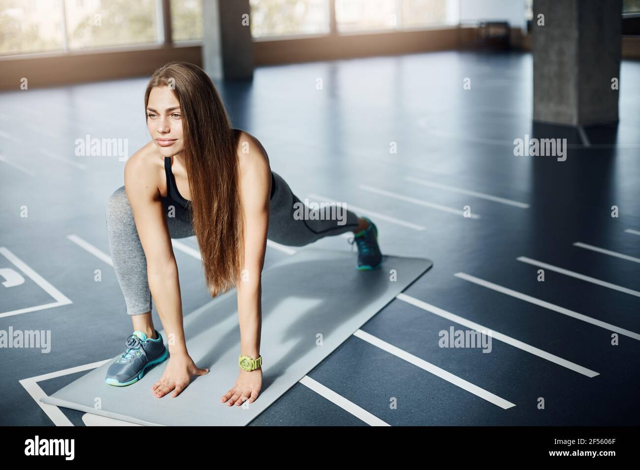 Concentrated female athlete stretching on a yoga mat early in the morning  in empty gym. Beautiful woman in her mid 30s taking care of her fit body  Stock Photo - Alamy