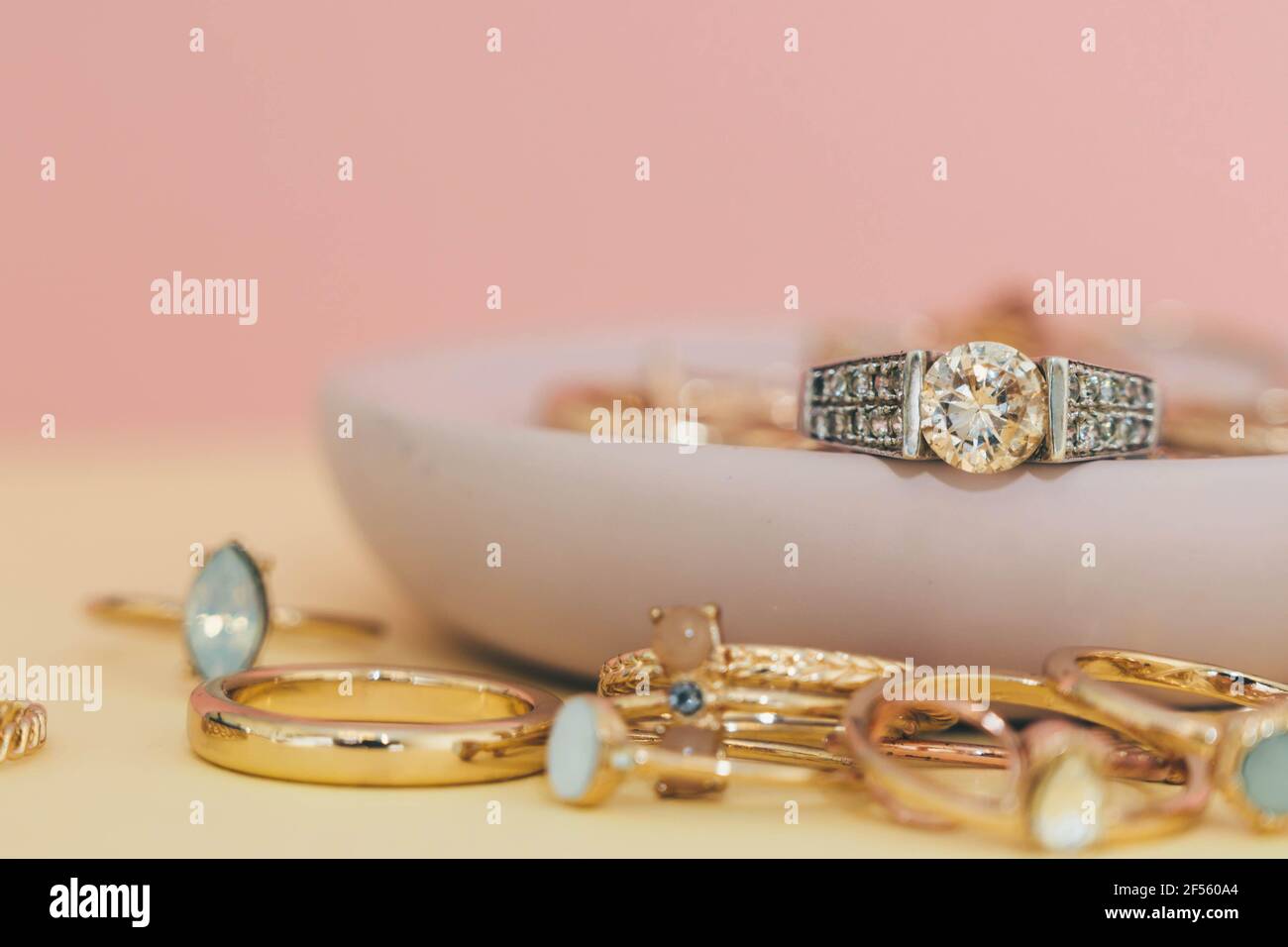 Shiny gold and silver jewellery on pastel pink and yellow background