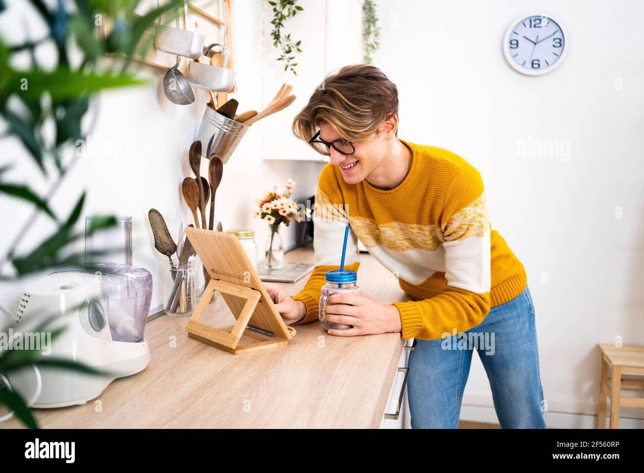 Young man using digital tablet while leaning on kitchen counter at home Stock Photo