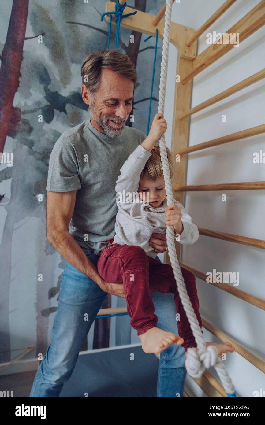 Father assisting son climbing rope at home Stock Photo