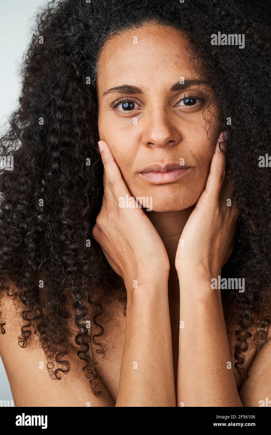 Serious curly haired woman touching face Stock Photo