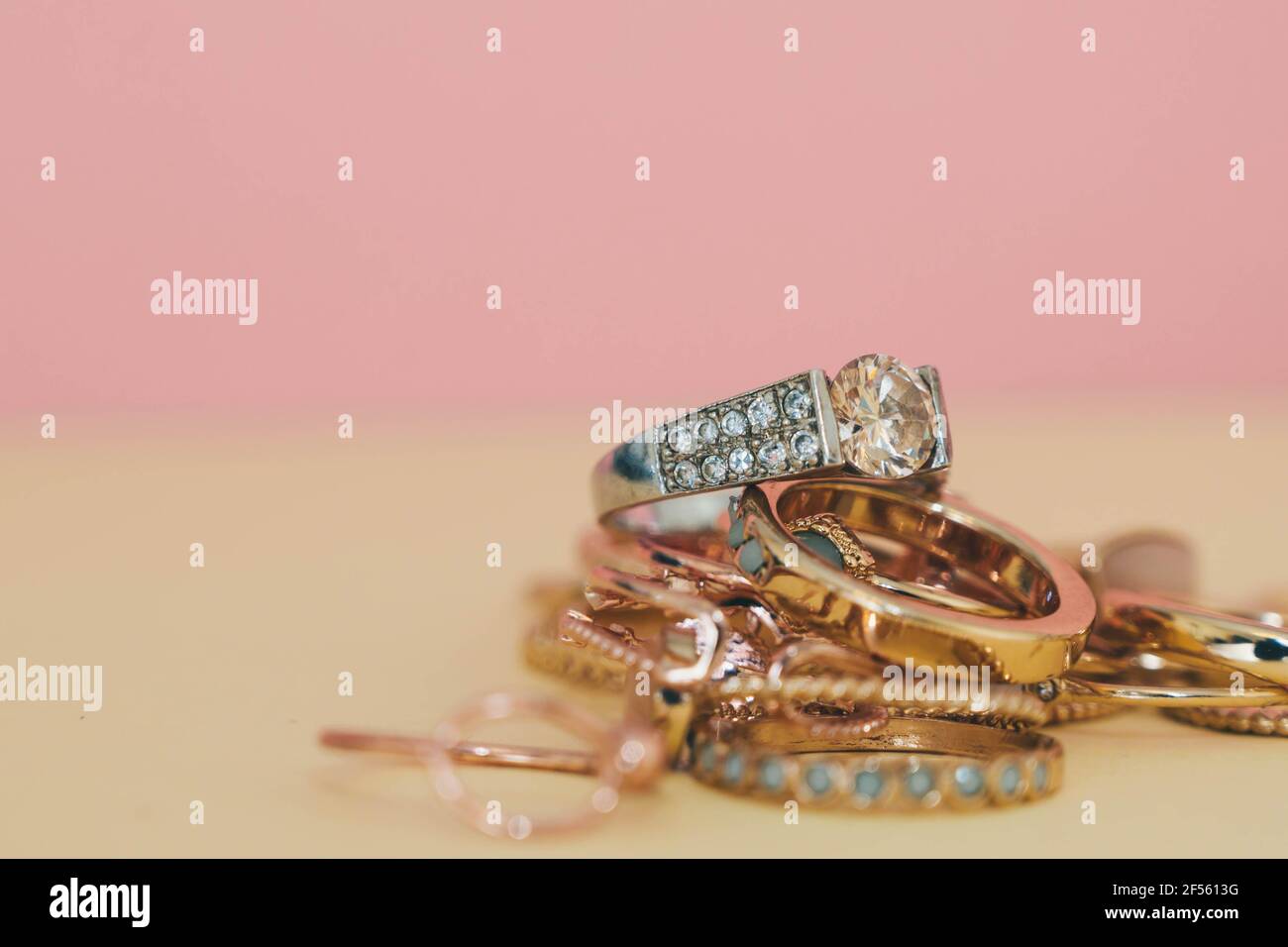Shiny gold and silver jewellery on pastel pink and yellow background