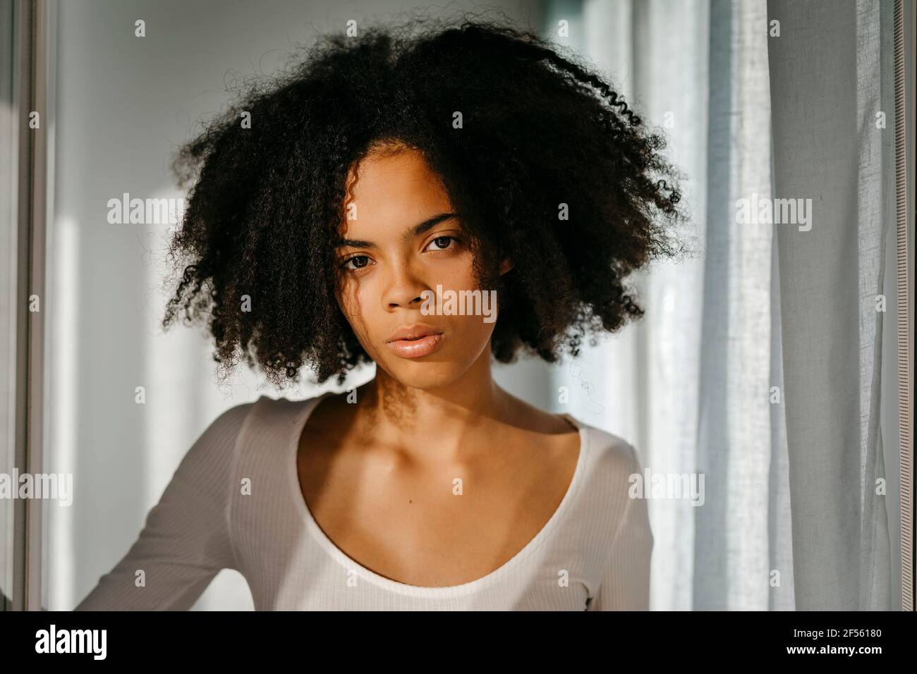 Serious woman with frizzy hair in bedroom at home Stock Photo
