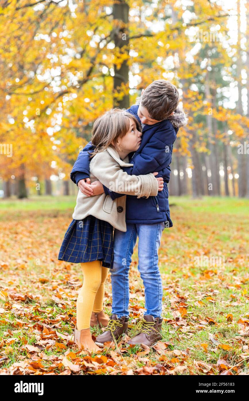 Sibling embracing while standing at forest Stock Photo