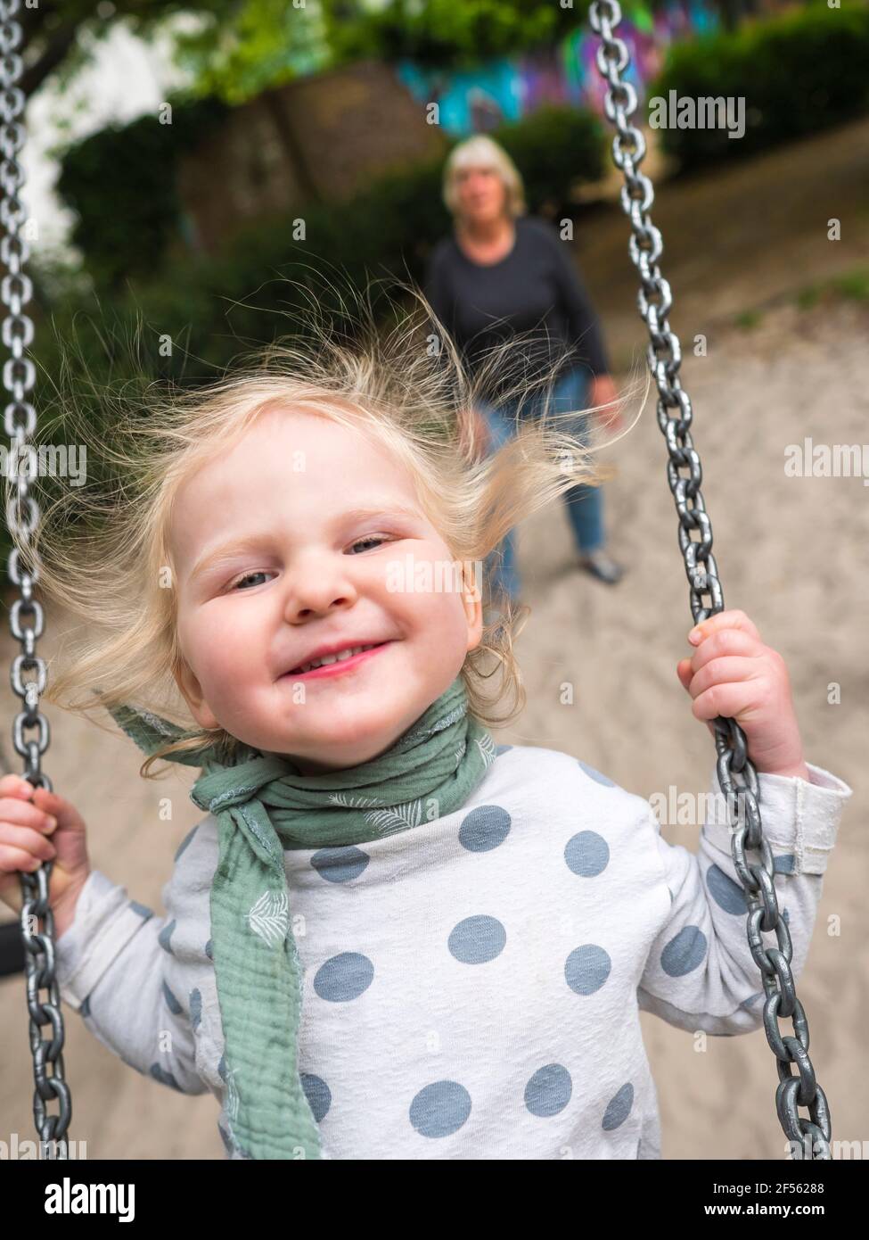 Cheerful girl on swing while grandmother standing at park Stock Photo