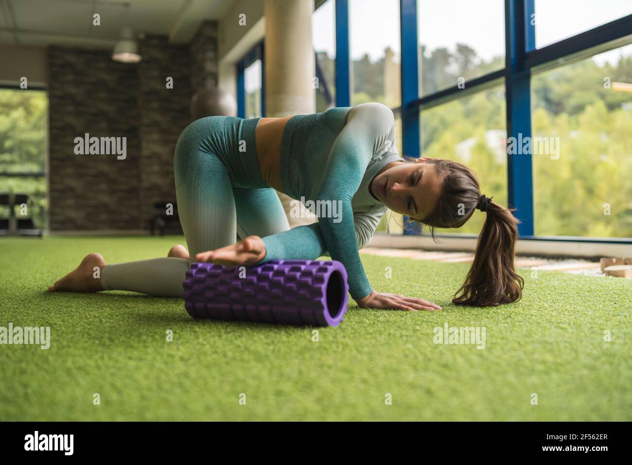Young sportswoman exercising on foam roller at health club Stock Photo