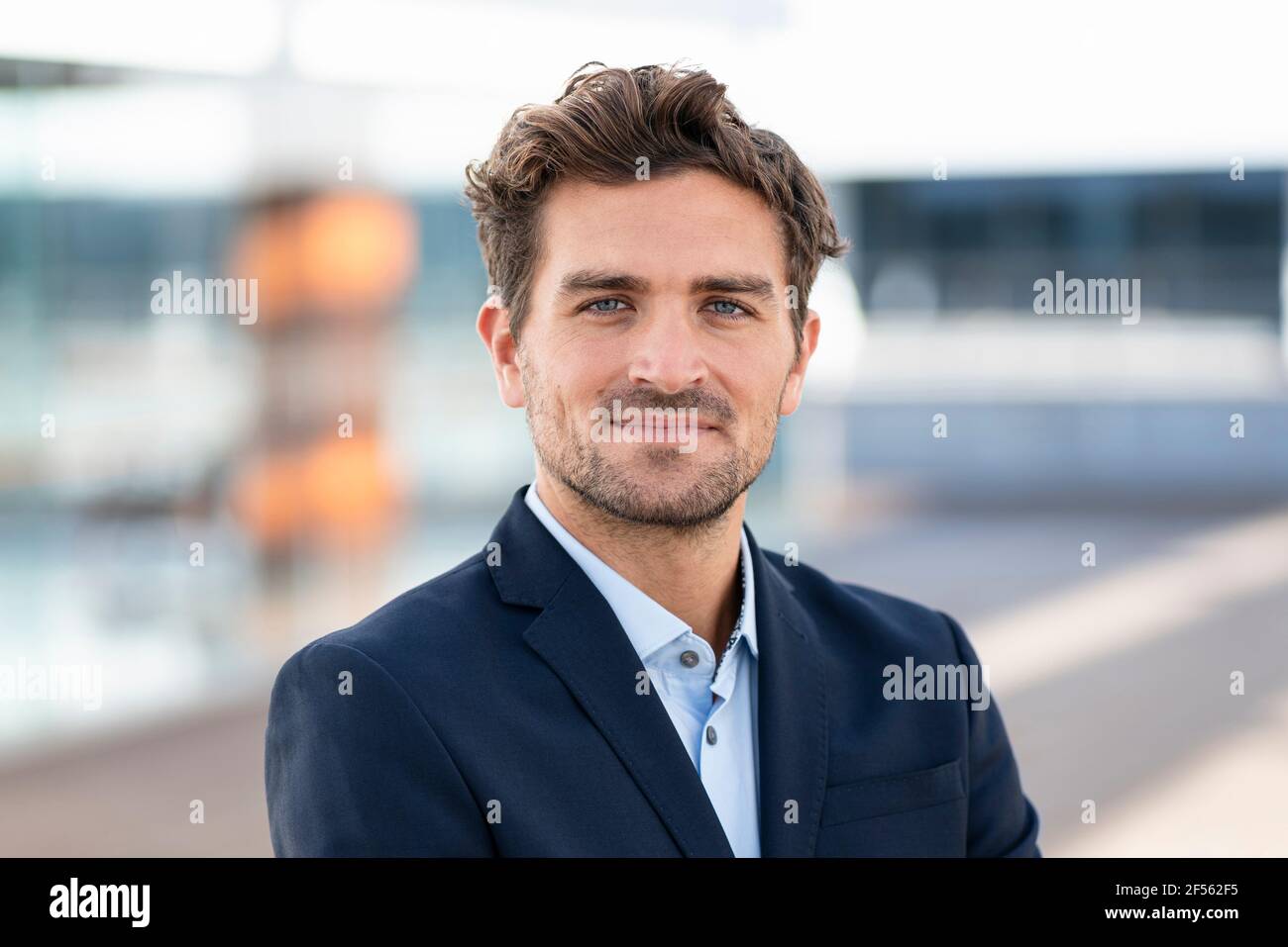 Smiling businessman staring while standing outdoors Stock Photo