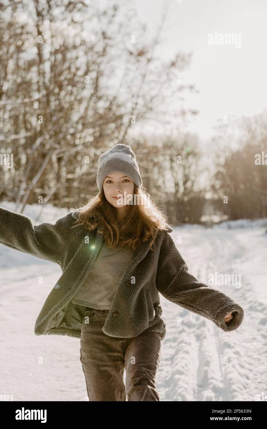 Portrait of beautiful teenage girl walking through snow toward camera