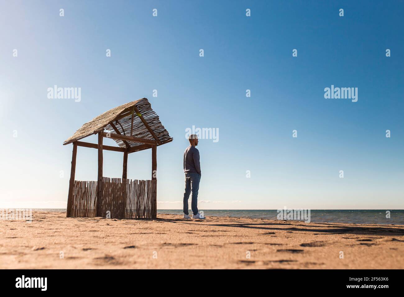 Man looking at sea view while standing on beach during sunny day Stock Photo