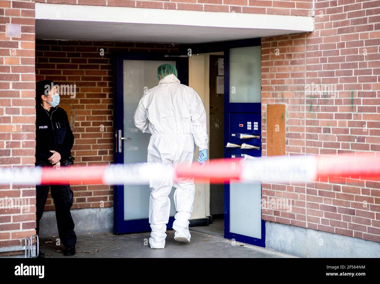Delmenhorst, Germany. 24th Mar, 2021. A forensics investigator enters an apartment building. A woman has died in a homicide. The 28-year-old victim was fatally injured with a knife, a police spokeswoman said. Credit: Hauke-Christian Dittrich/dpa - ATTENTION: Name plates on the doorbells and house number have been pixelated for legal reasons/dpa/Alamy Live News Stock Photo