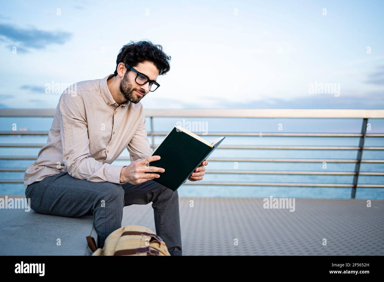 Smiling businessman reading diary while sitting on bench in front of blue sky Stock Photo