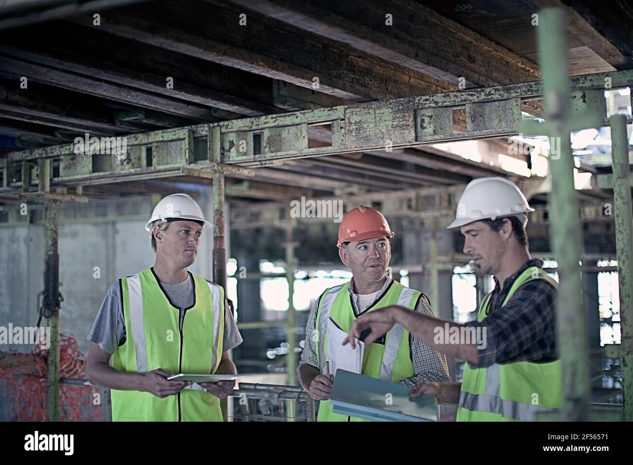 Male construction worker discussing with coworkers at construction industry Stock Photo