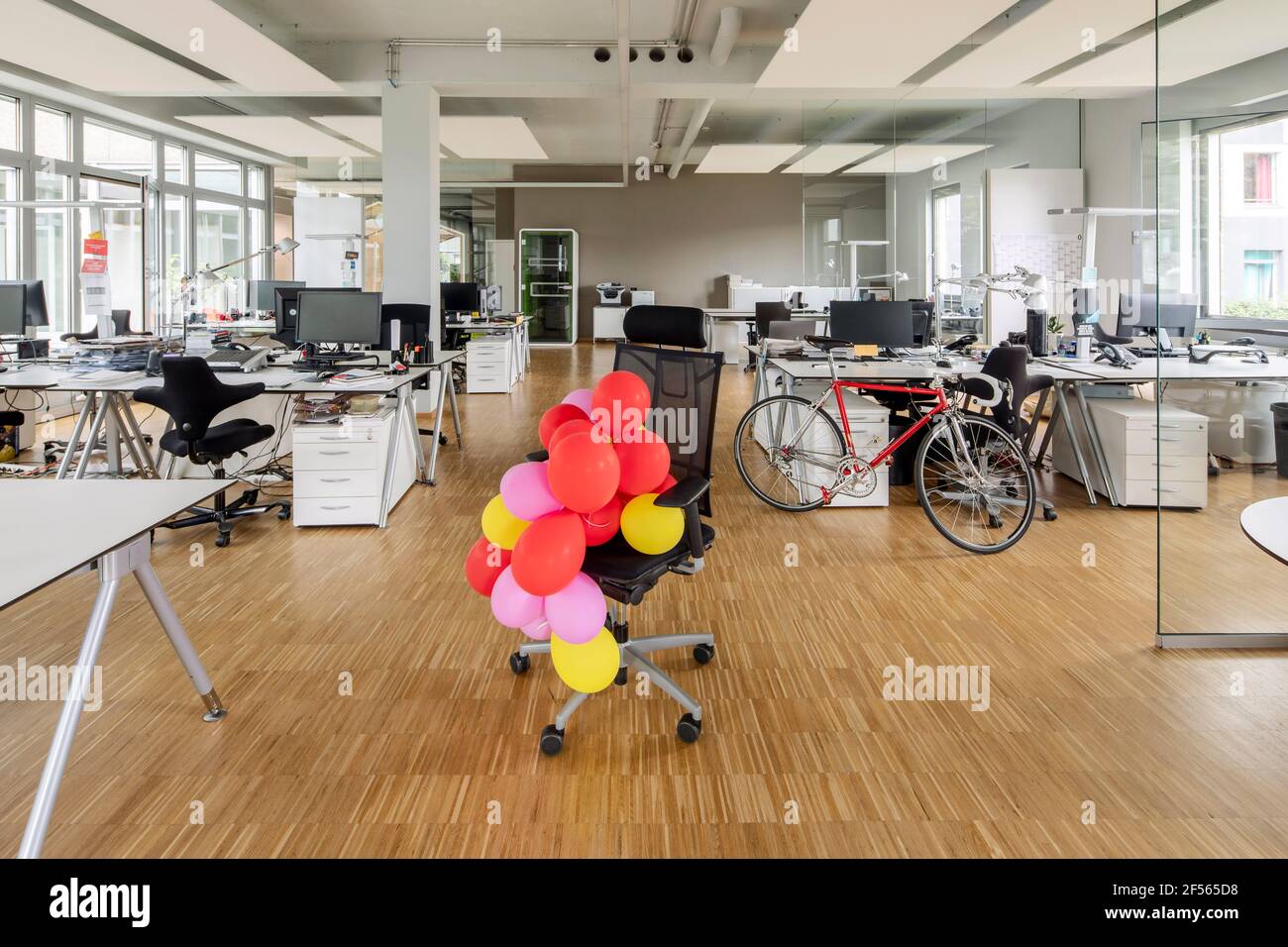 Bunch of balloons on chair in open plan office Stock Photo