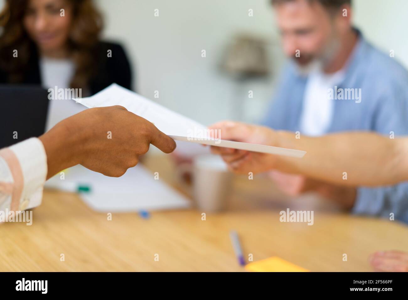 Coworkers passing document to each other at office Stock Photo