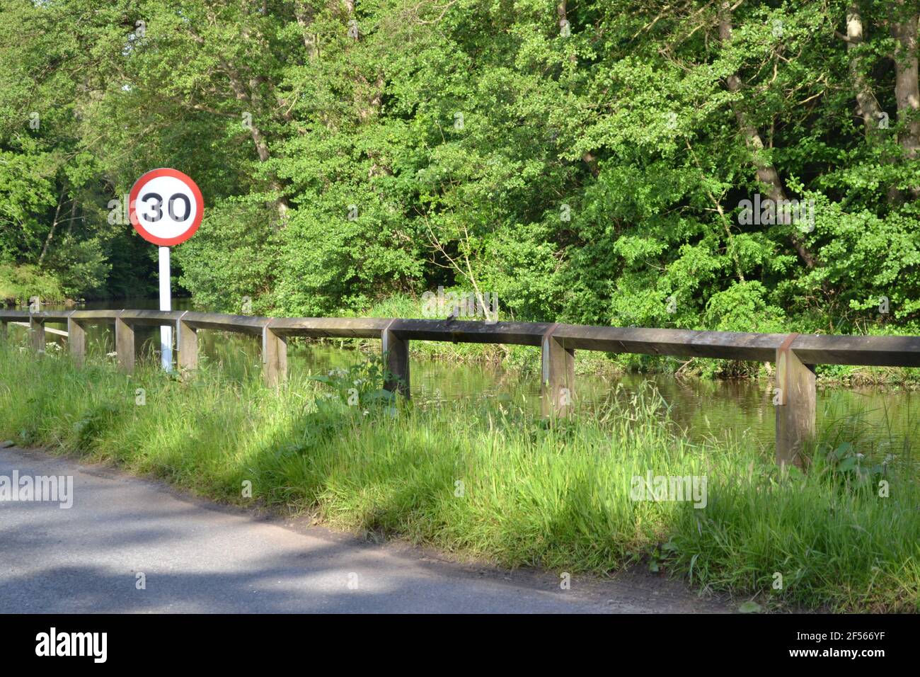 30mph Road Sign - Country Road Running Beside A River - North York Moors - Sunny Shinning - Thirty Miles Per Hour Regulatory Road Sign - Yorkshire UK Stock Photo