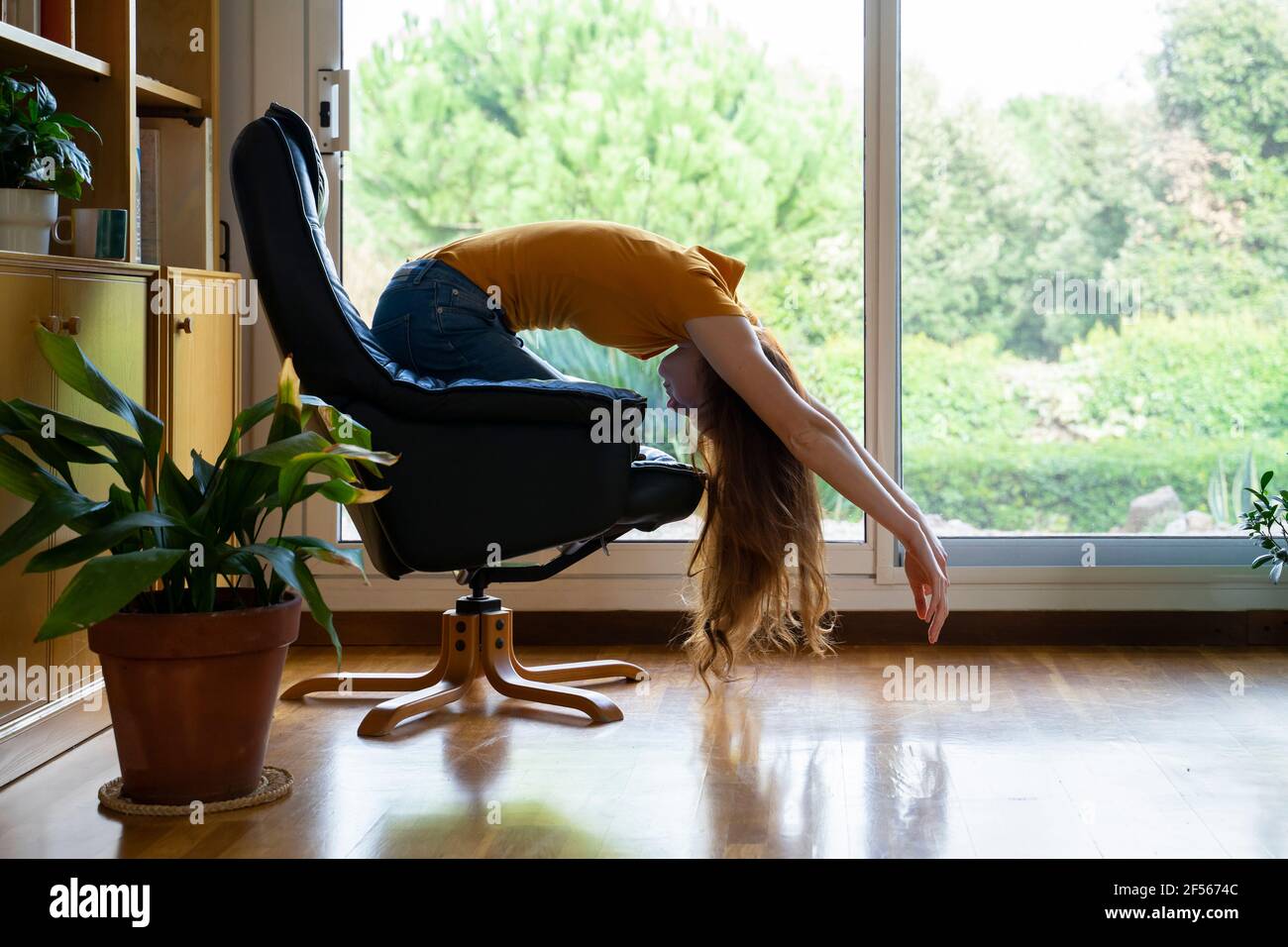 Young woman bending on chair at home Stock Photo