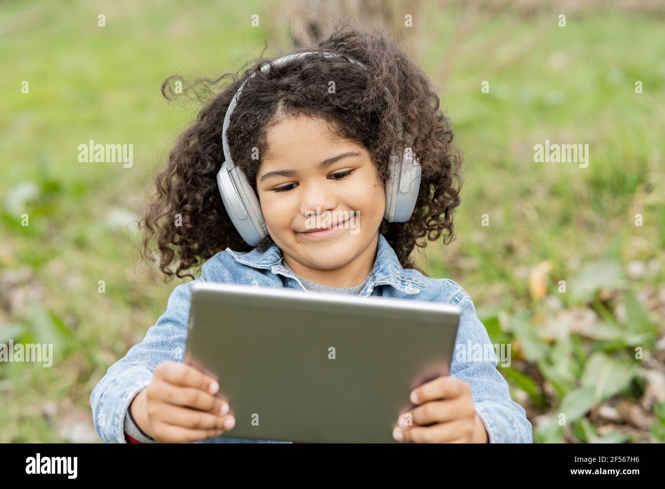 Boy using digital tablet while listening music in nature Stock Photo