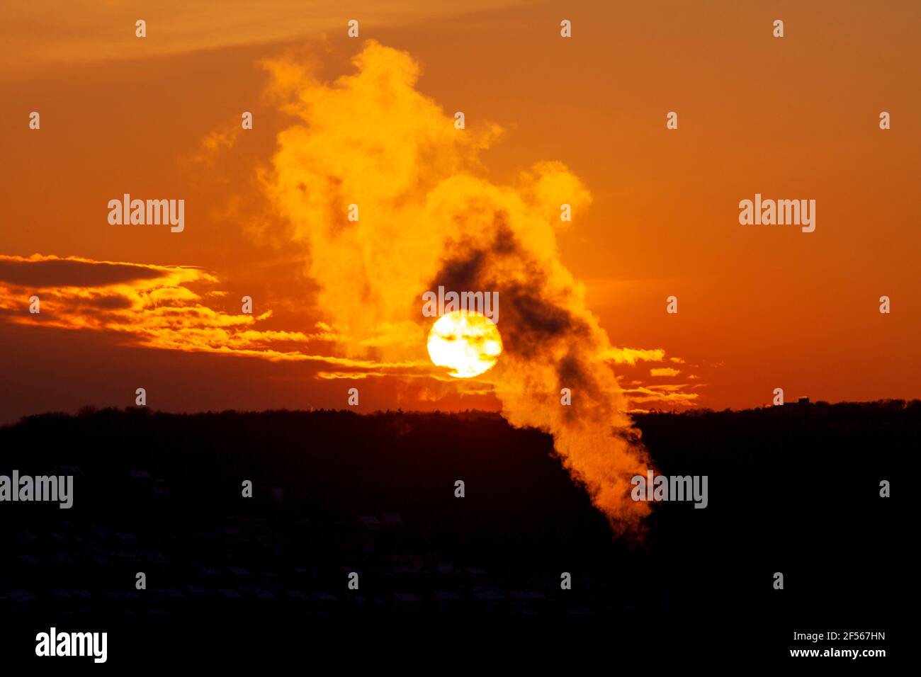 Steam from cogeneration plant floating against sky at moody sunset Stock Photo