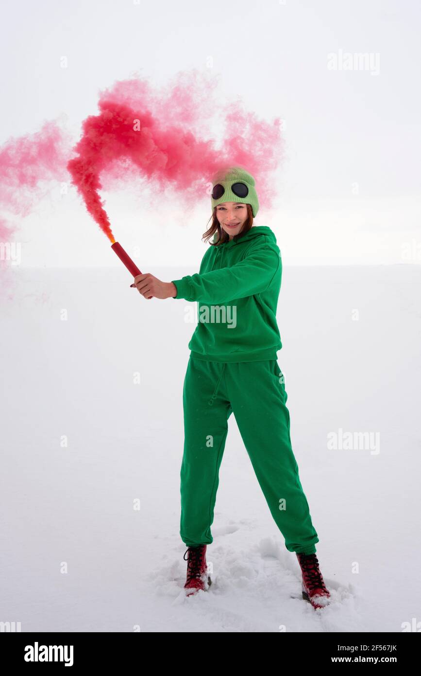 Distress flare held by woman in green costume against sky Stock Photo