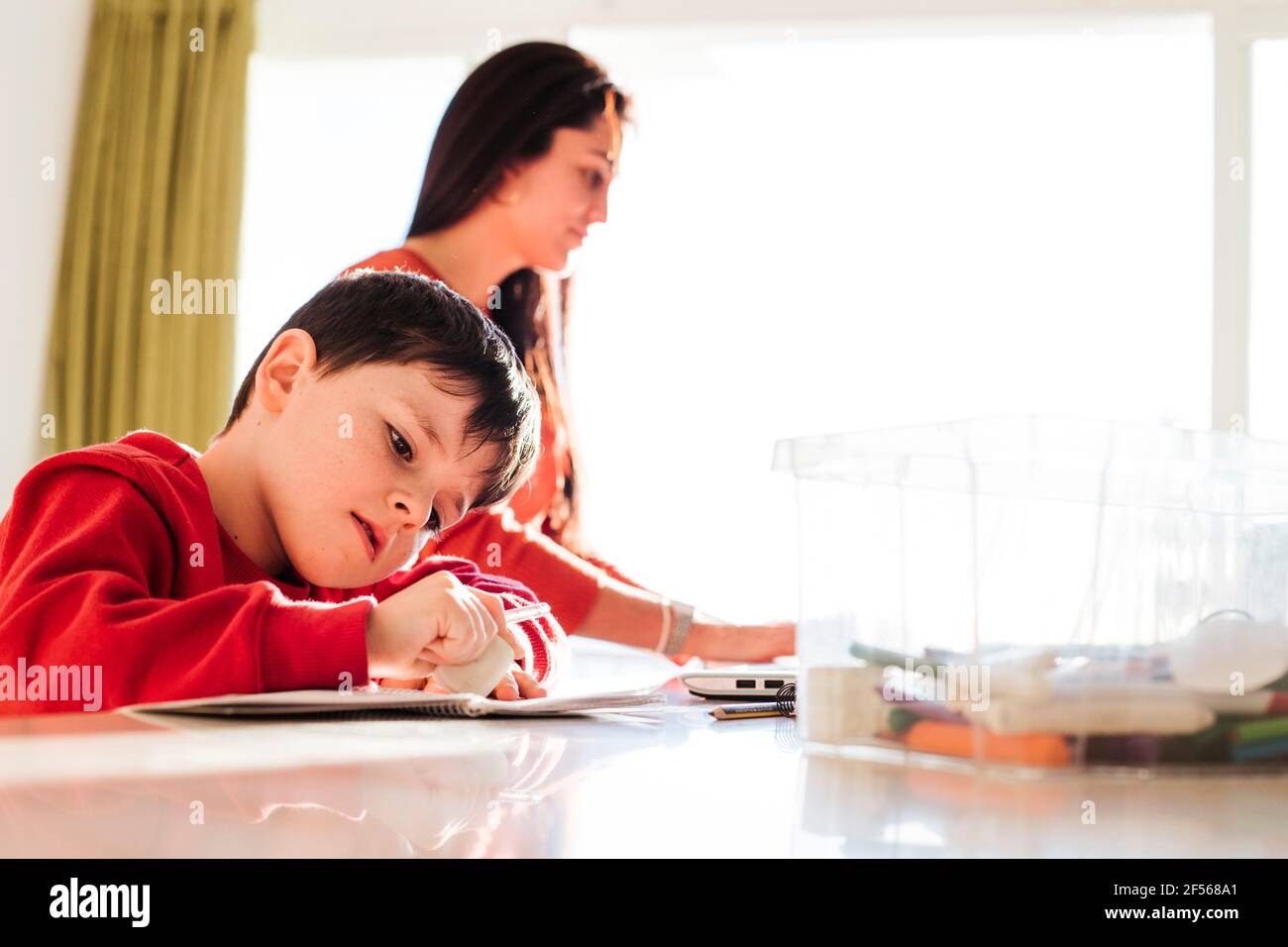 Boy studying while mother working at home Stock Photo